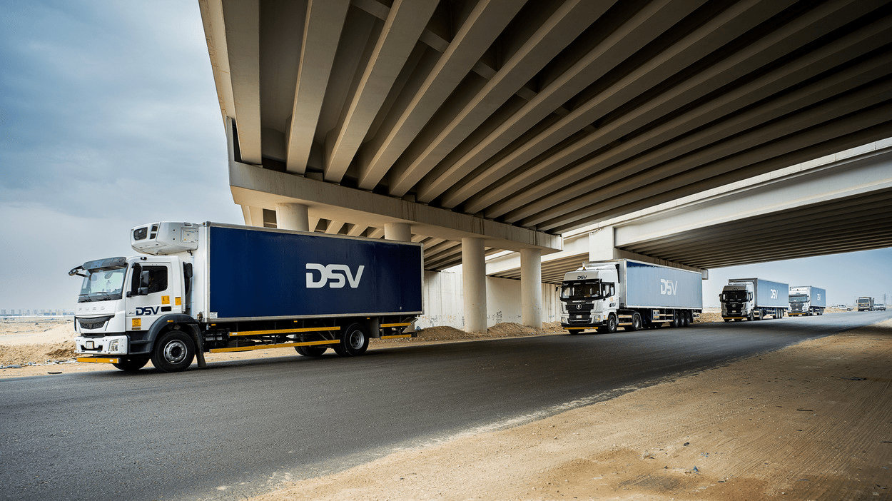 4 DSV-lastebiler kjører etter hverandre under en bro.